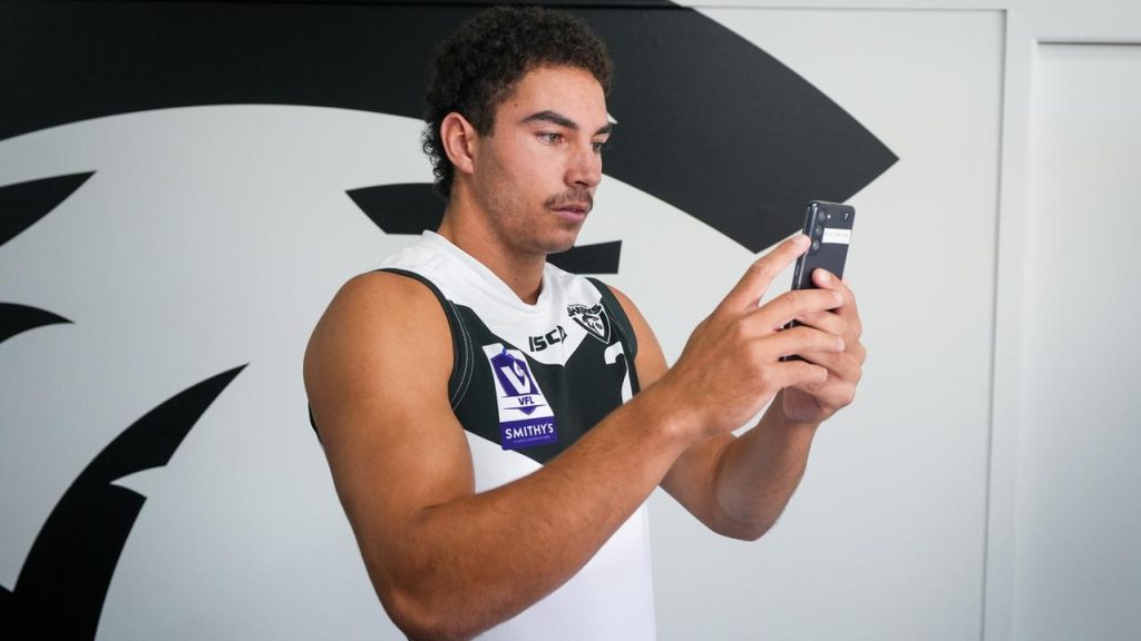 Football player looking at tech on his phone