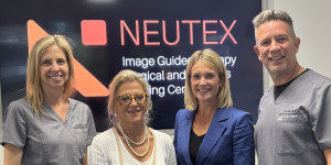 Four people stand smiling in front of a sign for NEUTEX (Image-Guided Therapy, Surgical and Robotics Training Centre). From left to right: Dr Laetitia de Villiers, Nadine Hans, Linnea Burman, and Dr Hal Rice.