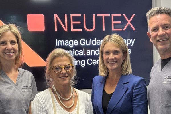 Four people stand smiling in front of a sign for NEUTEX (Image-Guided Therapy, Surgical and Robotics Training Centre). From left to right: Dr Laetitia de Villiers, Nadine Hans, Linnea Burman, and Dr Hal Rice.
