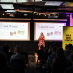 A startup founder pitches on stage in front of a projected presentation titled "50% Global PhD Dropout" during NextGen Demo Night.