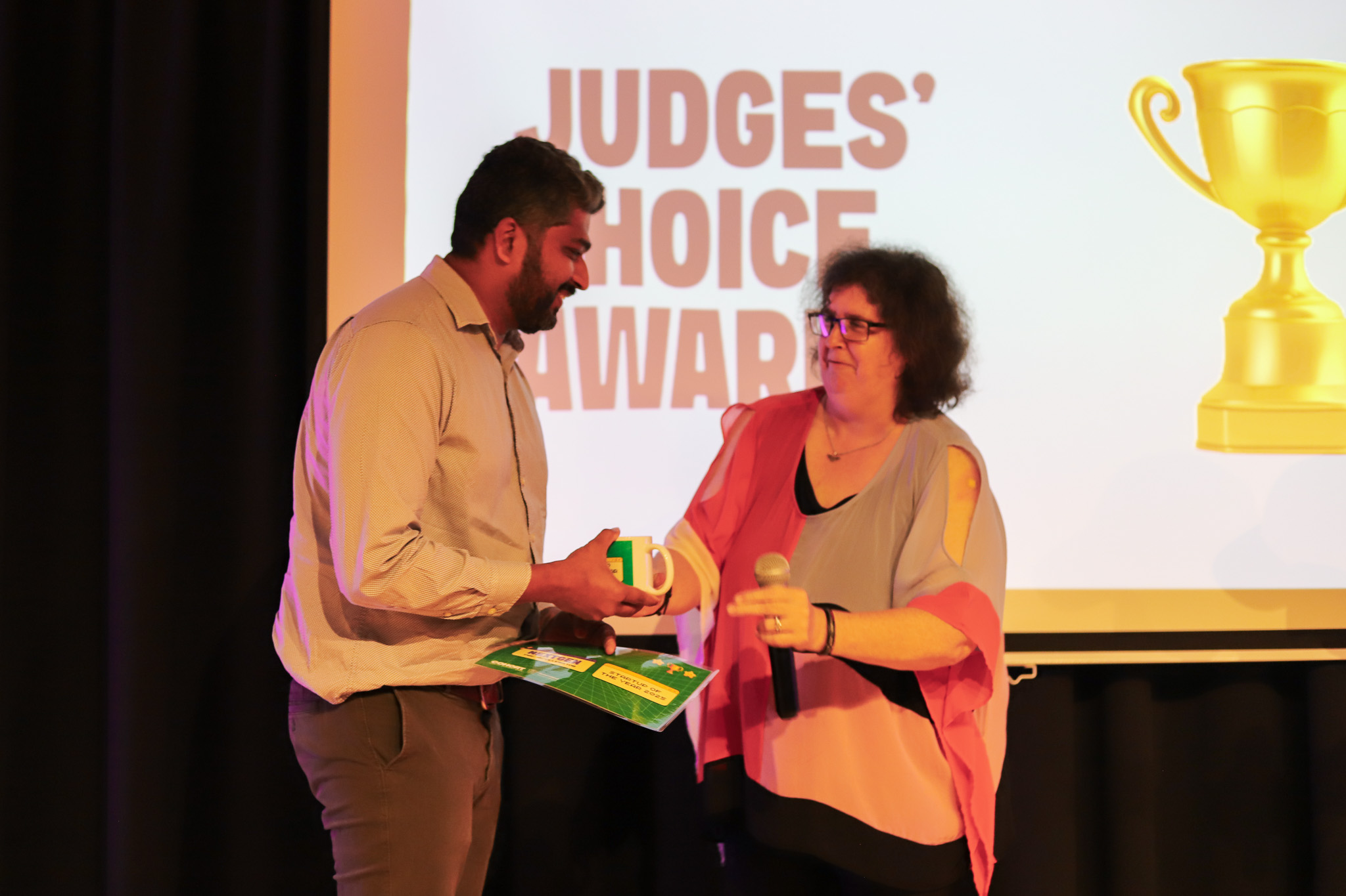 NeoGlycis founder accepts the Judges’ Choice Award from a program facilitator on stage at NextGen Demo Night.