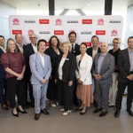 Group of senior representatives from Griffith University, Thermo Fisher Scientific and the Gold Coast Health and Knowledge Precinct posing in front of a co-branded media wall at the RDX building after signing a Memorandum of Understanding.