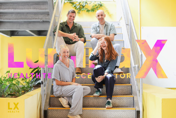 Team from the LuminaX HealthTech Accelerator 2026 cohort sitting on stairs at Cohort Innovation Space with branding overlay