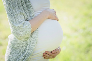 Pregnant woman holding her belly outdoors in a natural setting