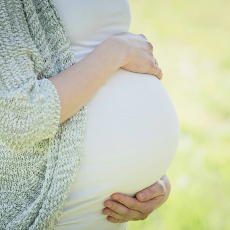 Pregnant woman holding her belly outdoors in a natural setting