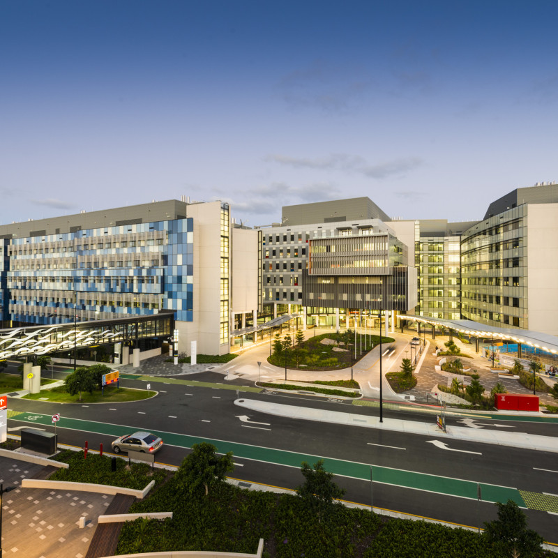 Exterior view of Gold Coast University Hospital following its opening in 2013, showing the modern multi-building hospital facility and landscaped entrance at dusk.