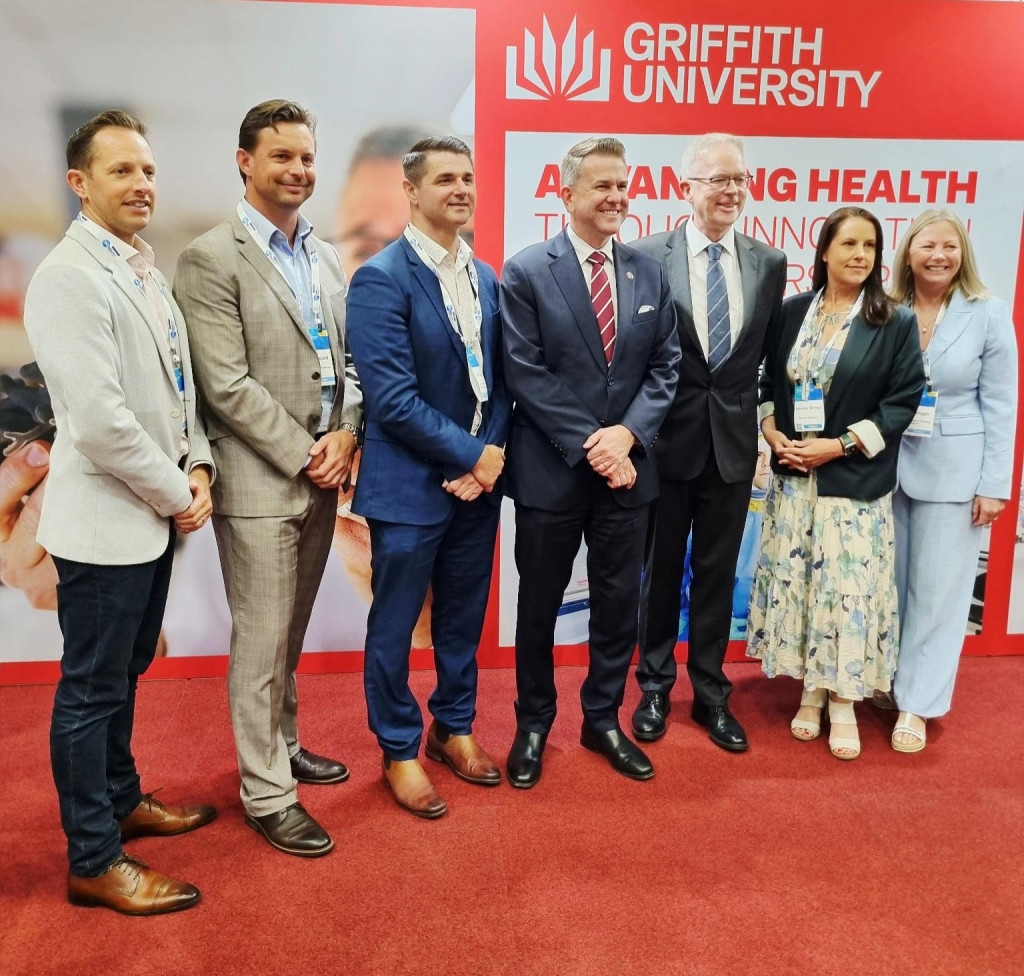 Griffith University and Burnet Institute representatives discuss their new partnership at the Institute for Biomedicine and Glycomics exhibition stand during AusBiotech 2026 on the Gold Coast.