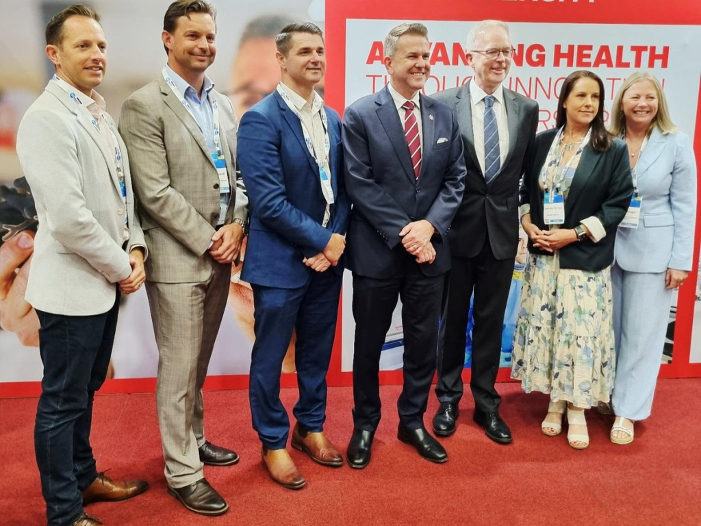 Griffith University and Burnet Institute representatives discuss their new partnership at the Institute for Biomedicine and Glycomics exhibition stand during AusBiotech 2026 on the Gold Coast.