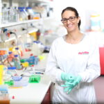 Dr Lara Herrero standing at a bench in a lab